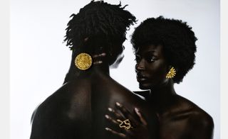Two models. Female wearing a gold half circle ear ring, a large gold ring and a snake shaped ring.