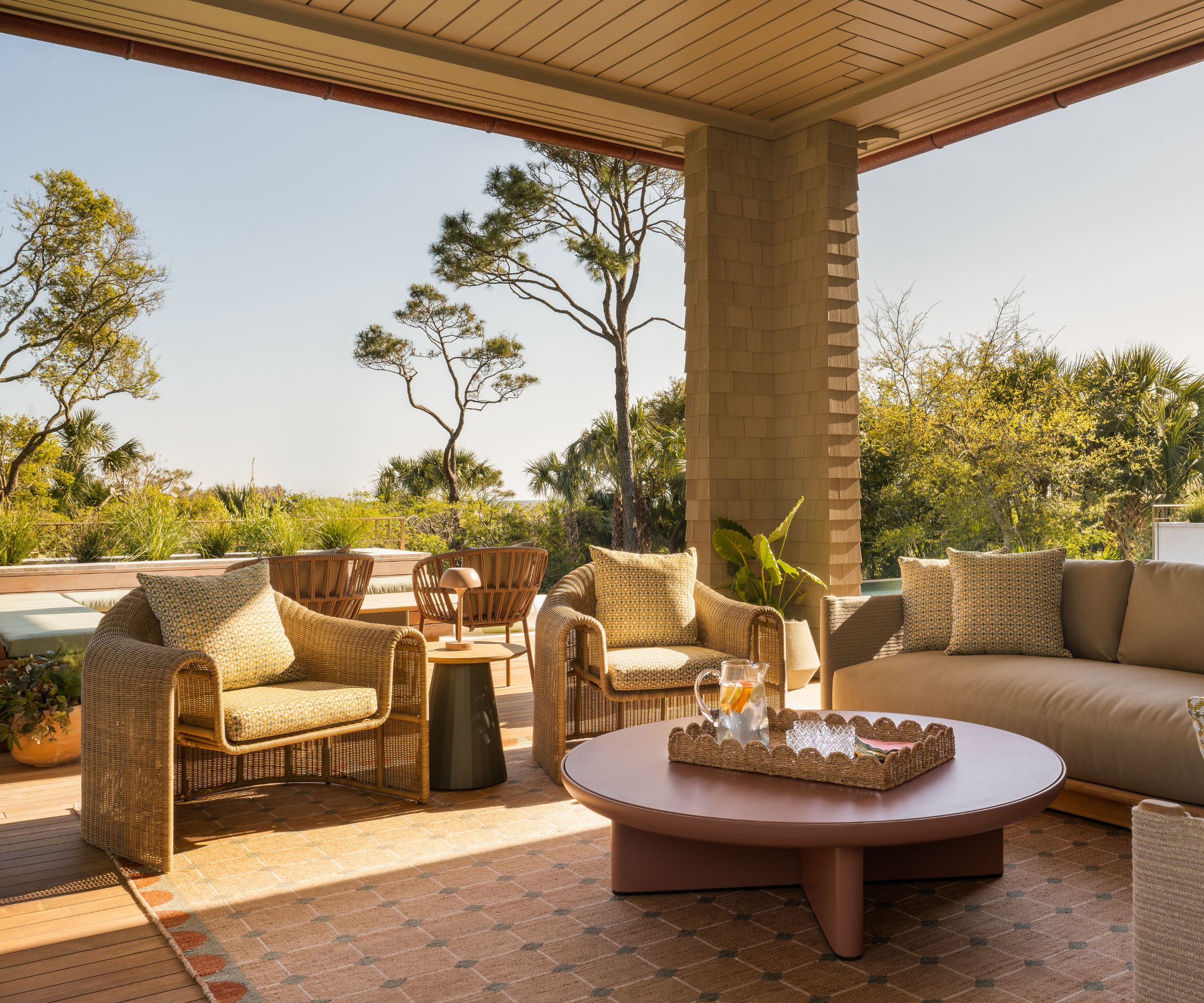 Outdoor living room with basket chairs, an outdoor rug and a round soft pink coffee table