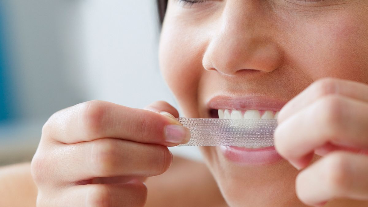 young woman whitening her teeth