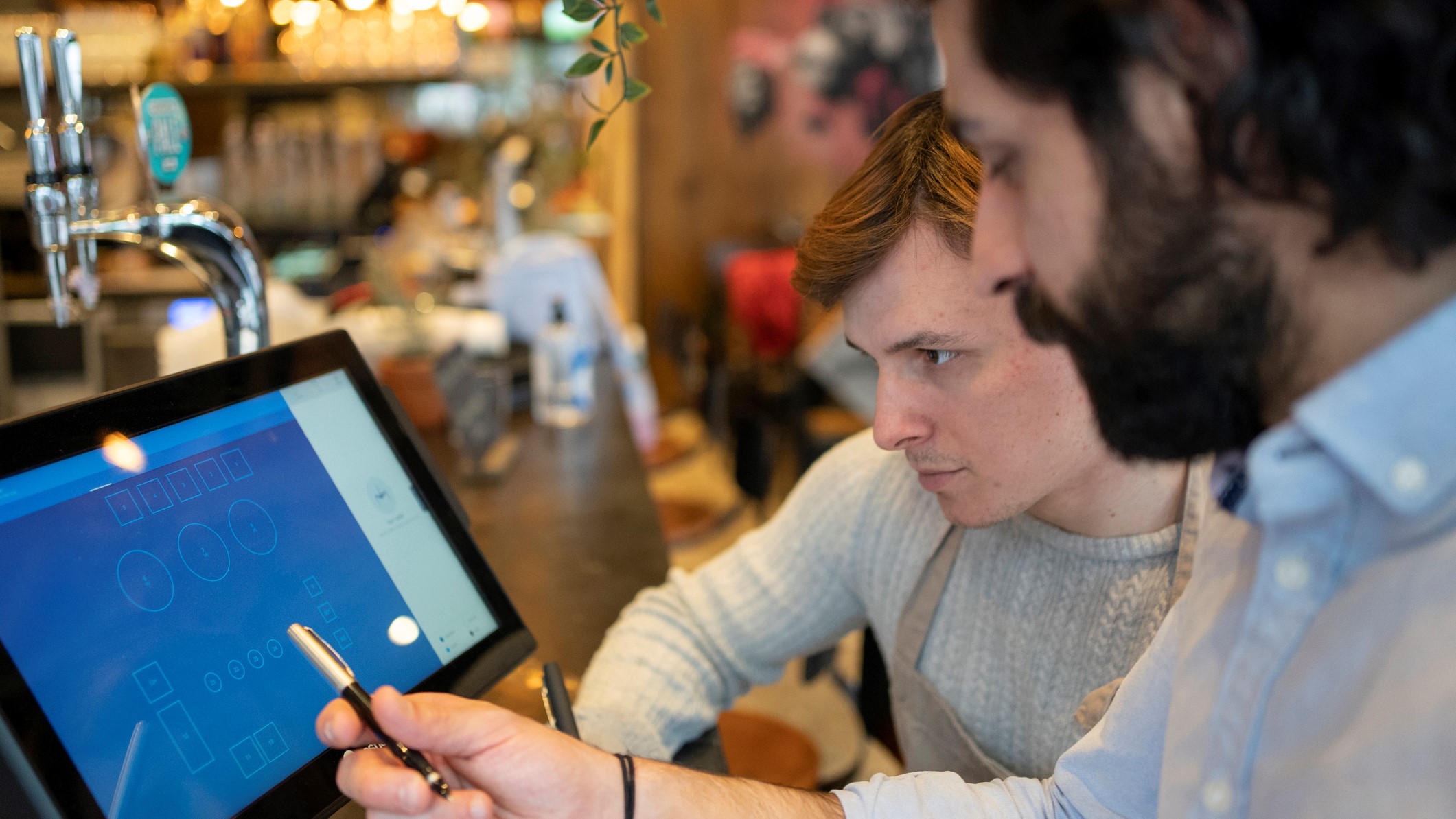 Two hospitality workers look at a POS system together