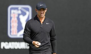Rory McIlroy walks off the green in front of a PGA Tour board