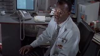 Samuel L. Jackson in glasses and a lab coat sitting in front of a computer in Jurassic Park