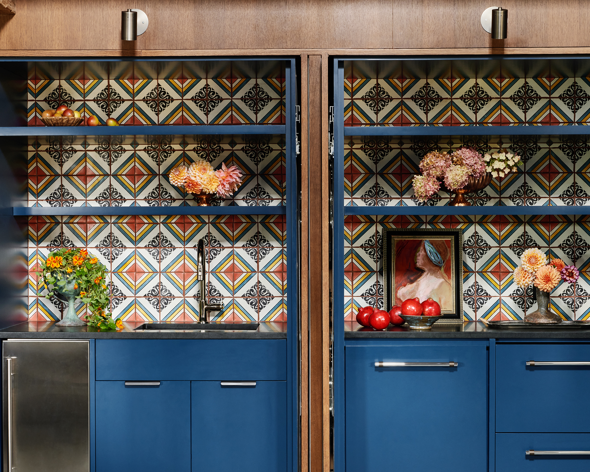 galley kitchen with blue cabinets and patterned tiles on the wall