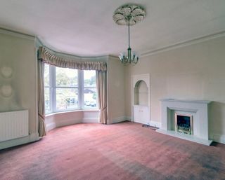 'Before' shot showing living room with cream walls, chandelier and red-pink carpet