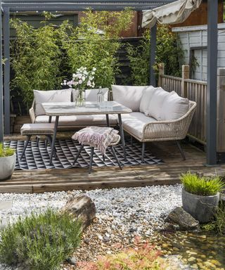 An outdoor area with pergola, L-shaped outdoor sofa, decking and gravel decor