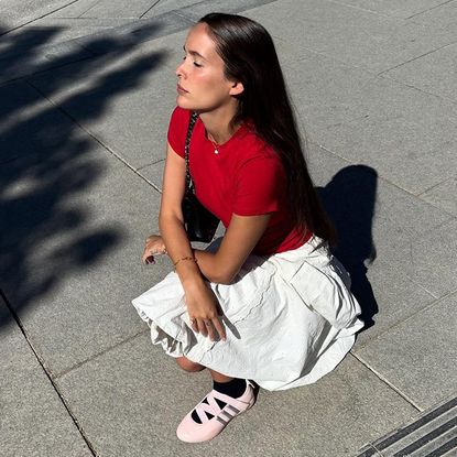 Helena wears white skirt, red tee, and pink adidas.