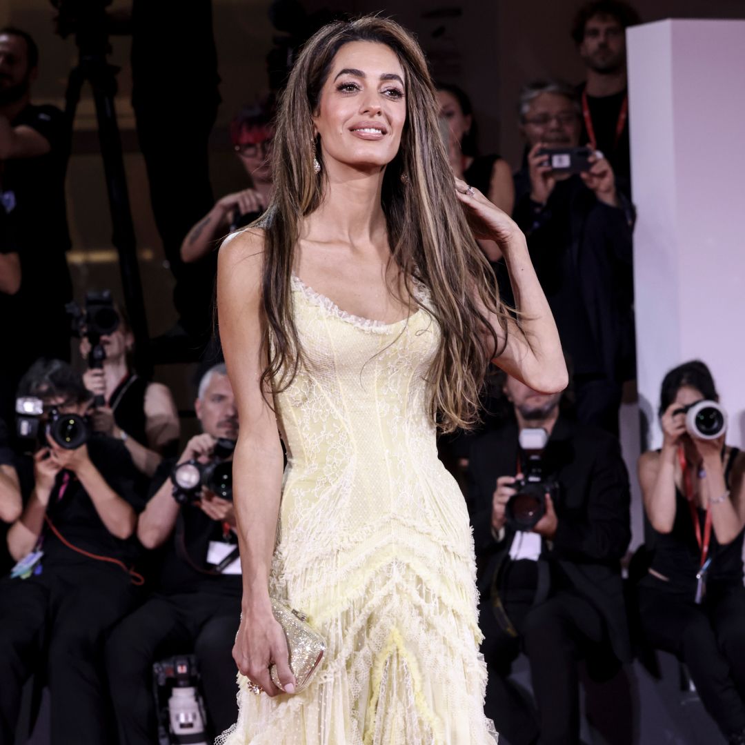 Amal Clooney wearing a yellow dress and posing on a red carpet