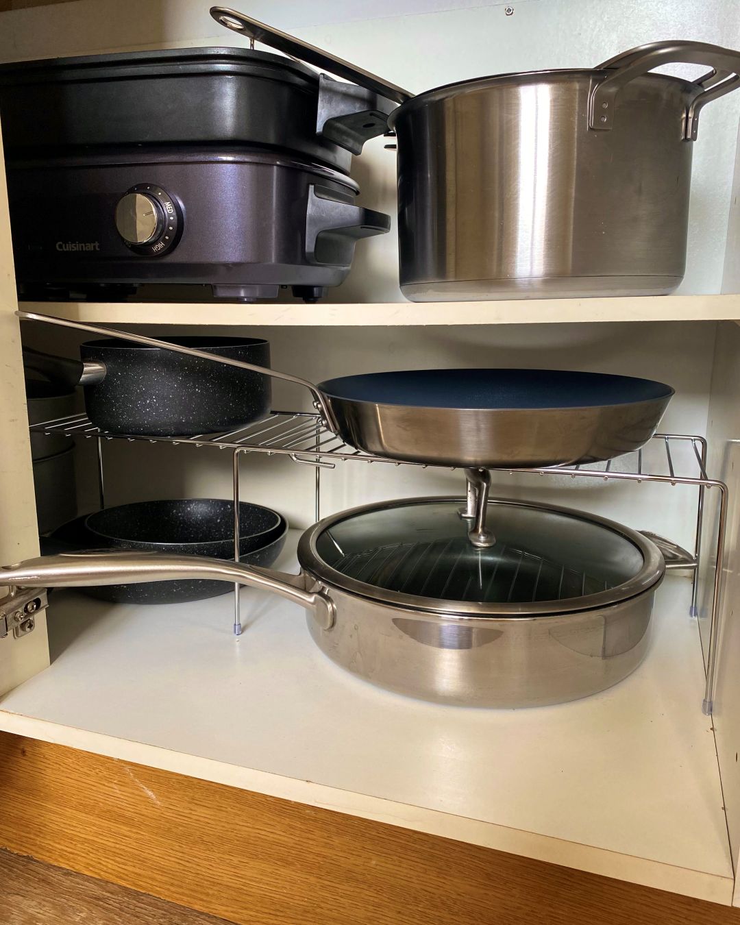 Inside a kitchen cupboard with a shelf stacking pans to show a small kitchen storage essentials