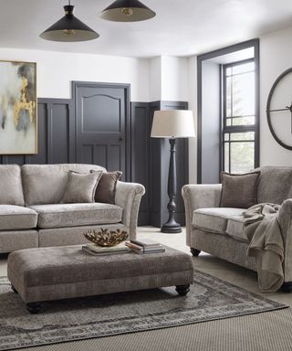 A gray living room with gray couches, coffee table, rugs, and a window