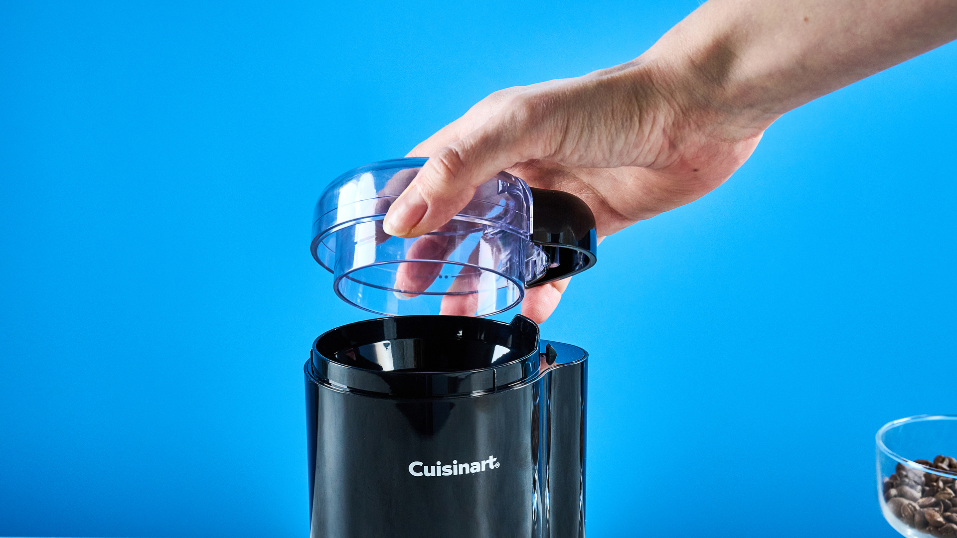 the cuisinart coffee grinder photographed against a blue background showing its blades and canister