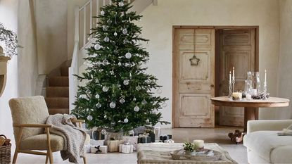 A decorated artificial Christmas tree with wrapped presents piled below