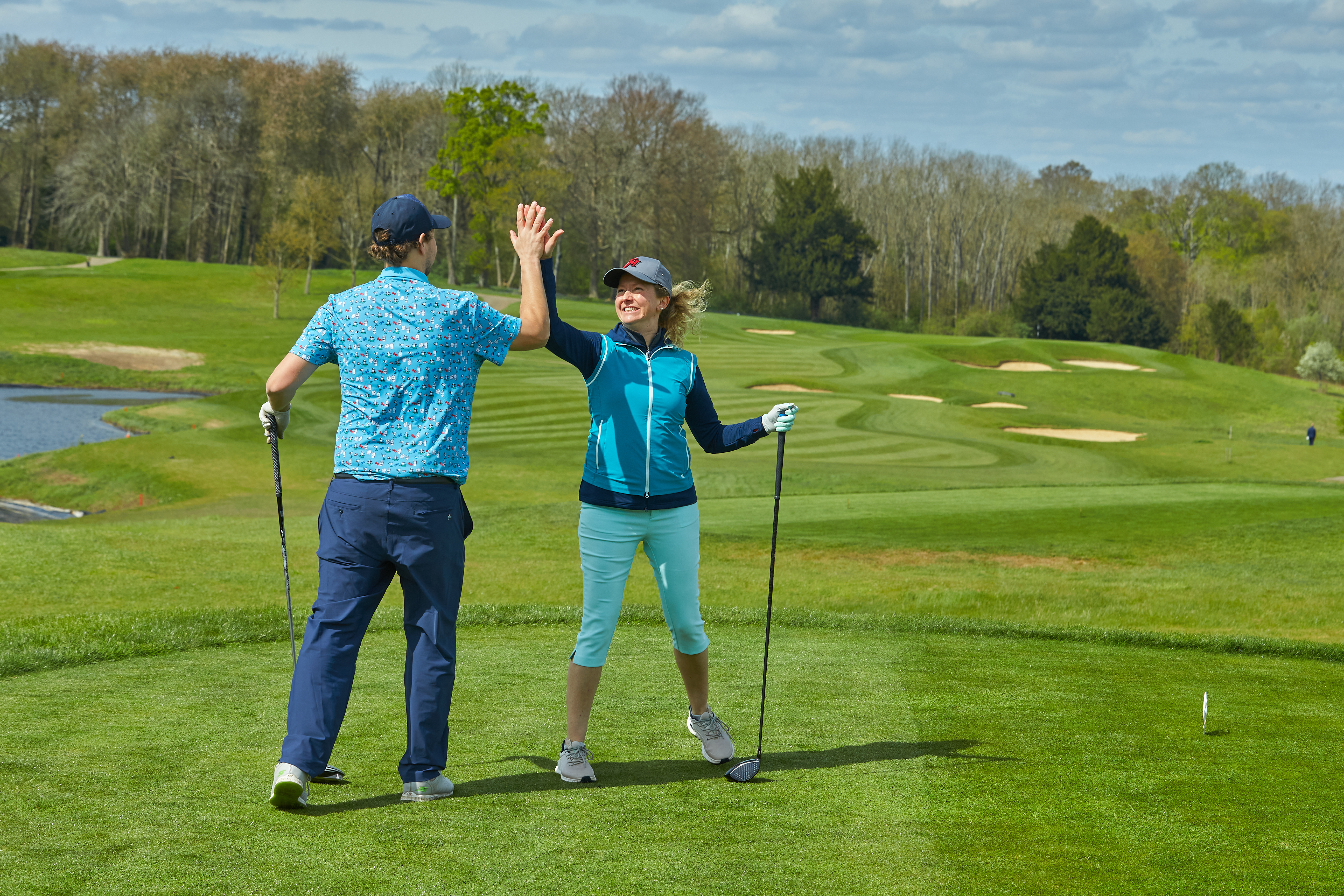 Two golfers high-fiving after one hits a good shot off the tee