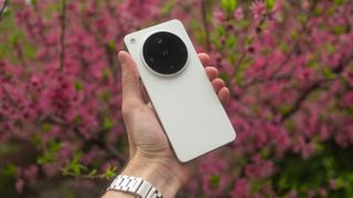 Oppo Find X8 Ultra phone held in a hand with pink flower in the background