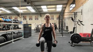 Kerrie Hughes doing weighted lunges with dumbbells in a gym