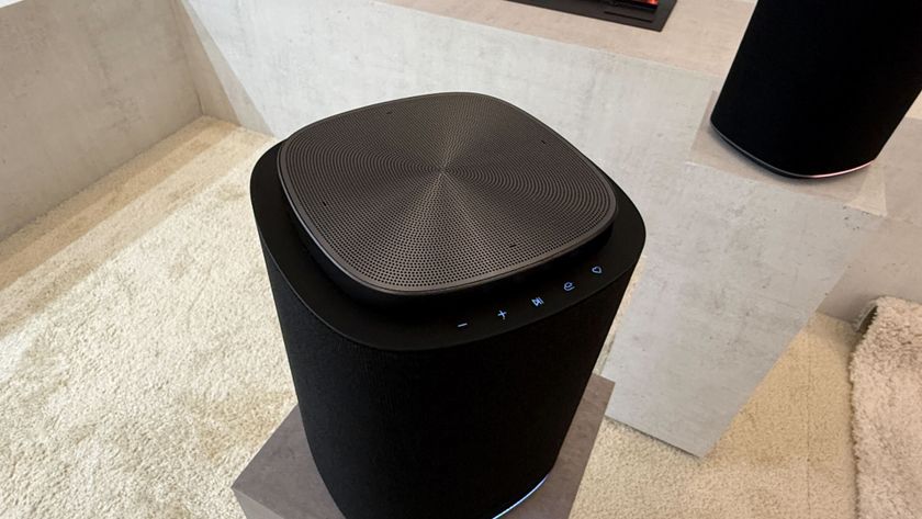 A top-down view of an LG speaker with a top-firing speaker grille and illuminated buttons 