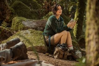 ashley sutton as frog researcher hannah sitting on a rock in season 3 episode 7 of yellowjackets