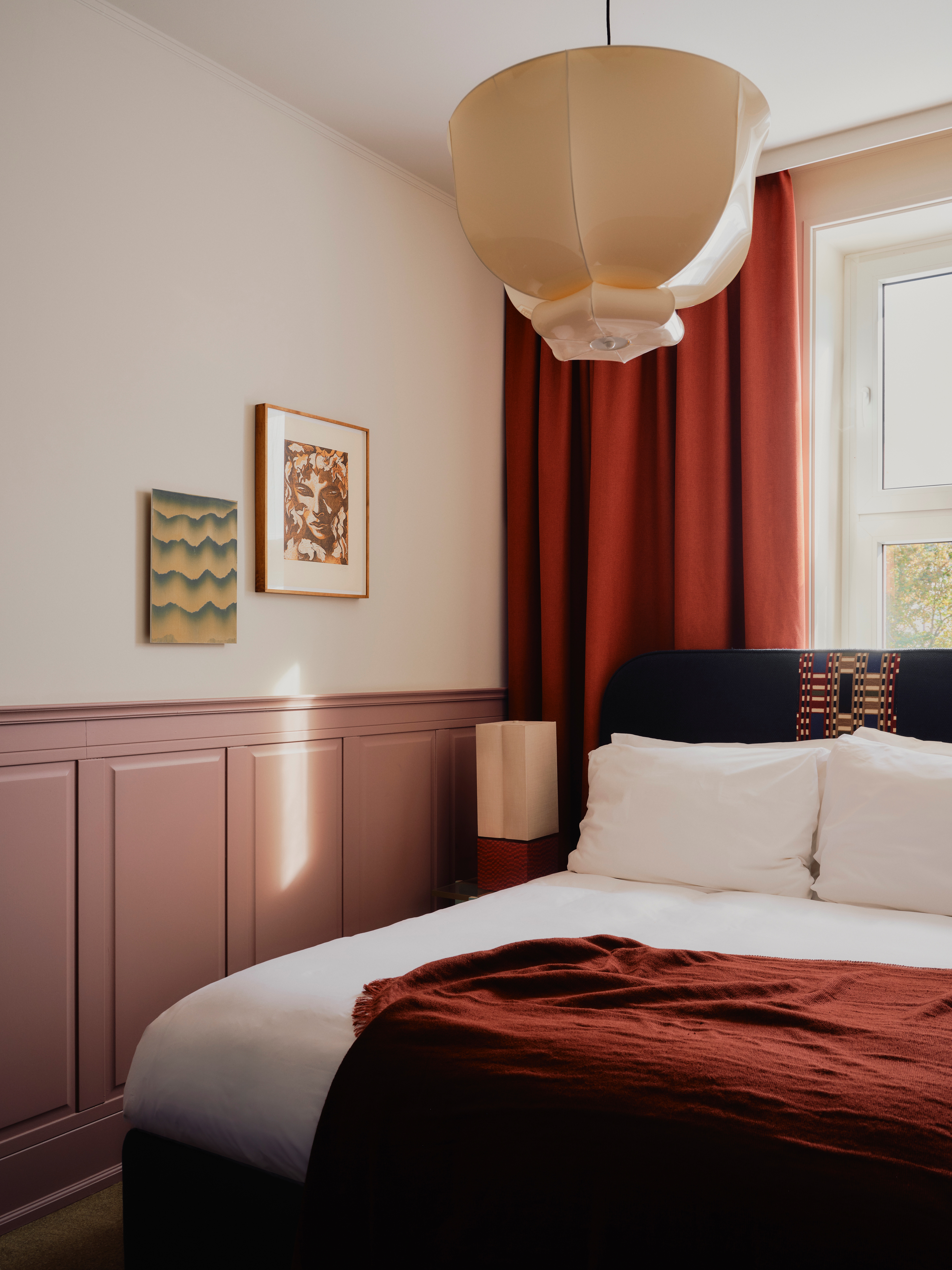 Interiors of a colorfully decorated hotel with a green, pink, and red palette, checkered or striped flooring, quirky, sculptural collectibles throughout, and lots of natural light.