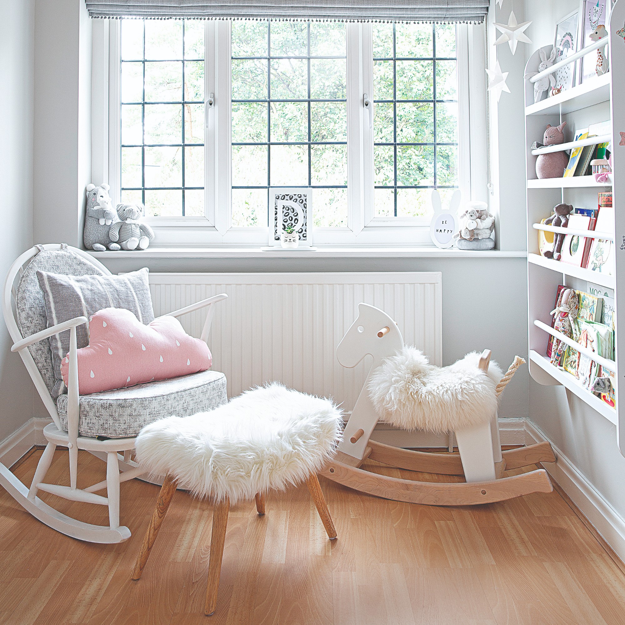 A small children's playroom with a rocking chair, a rocking horse and a bookshelf on the wall