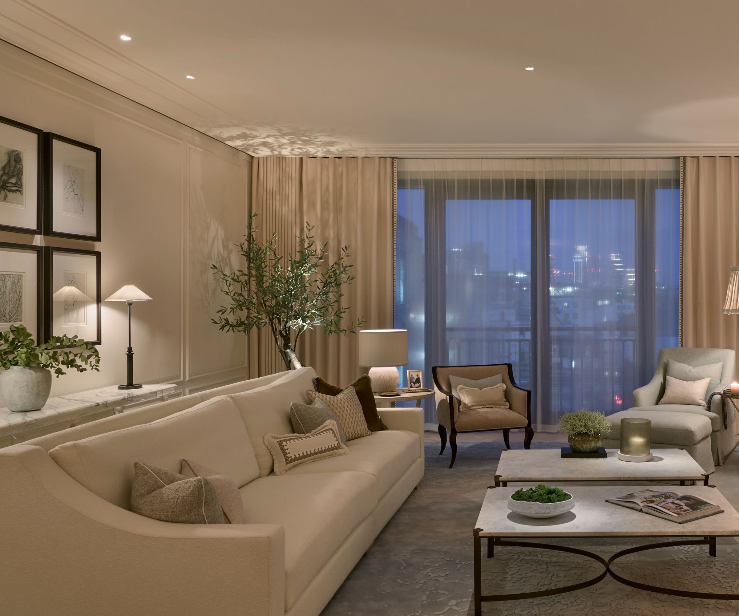 Cozy modern living room with lots of lamps, large whote sofa, gray rug, white marble and black square coffee tables, seating in background, artwork and greenery surround