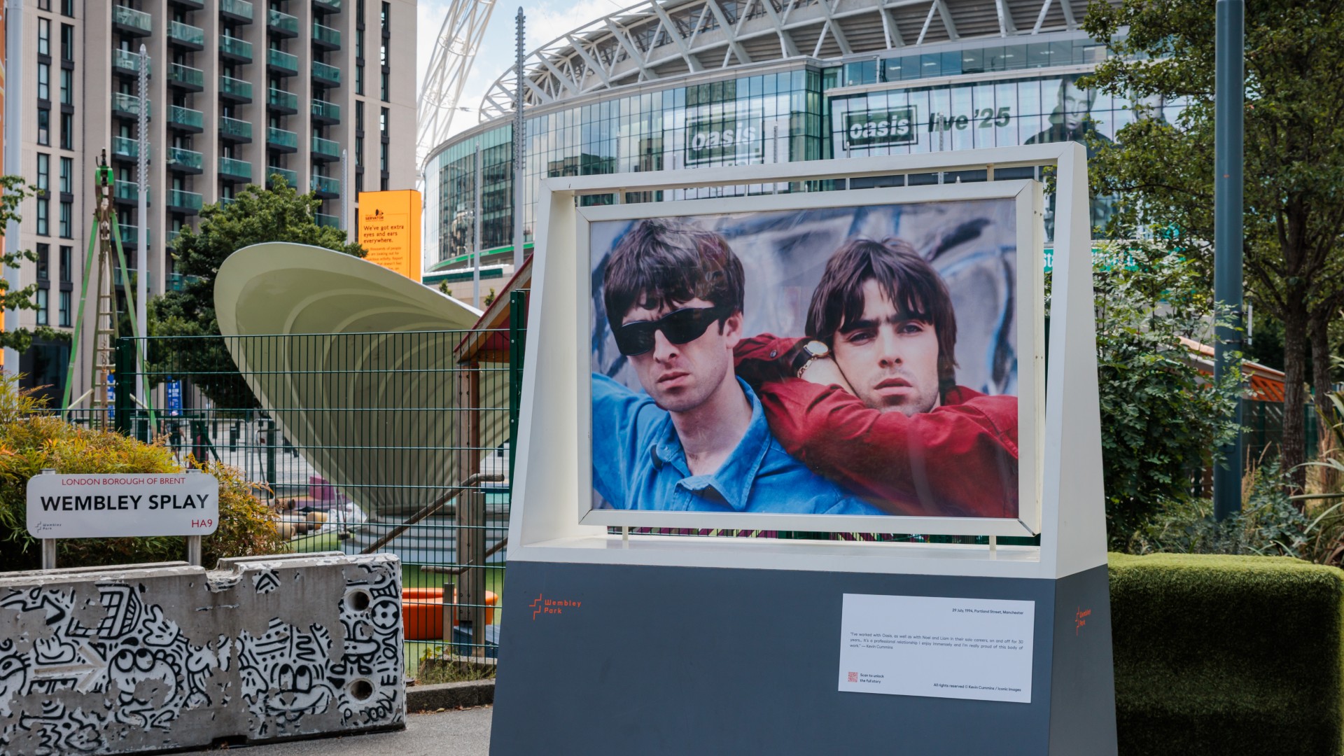 A framed photograph of the Gallagher brothers, Liam and Noel of the band Oasis, is on display outdoors in front of Wembley Stadium in London.