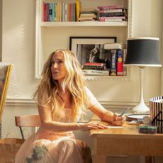 carrie bradshaw sits at a desk writing in a still from and just like that