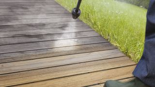 Wooden decking being sprayed with deck cleaner showing the before and after