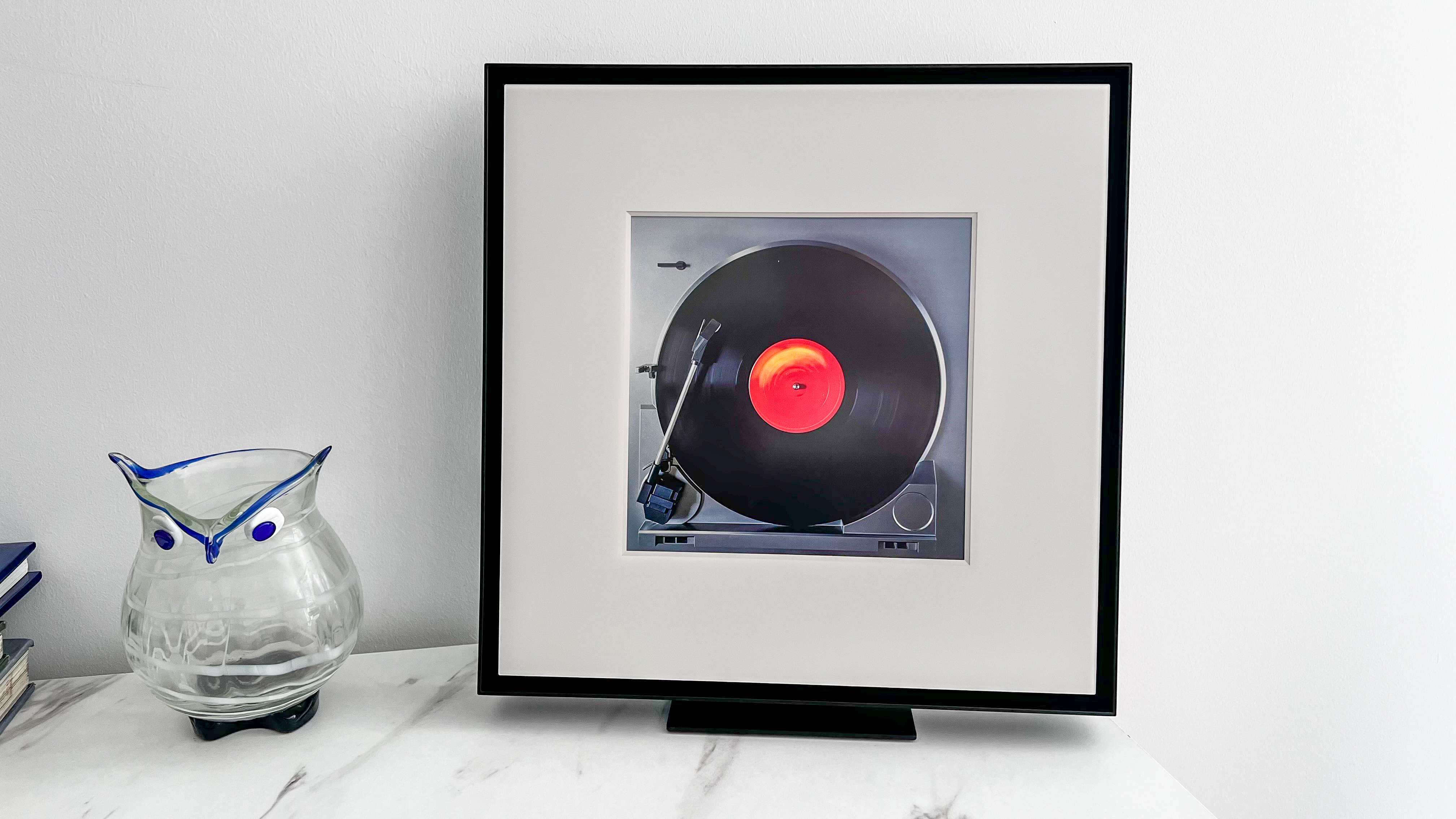 Samsung Music Frame on a table beside a vase