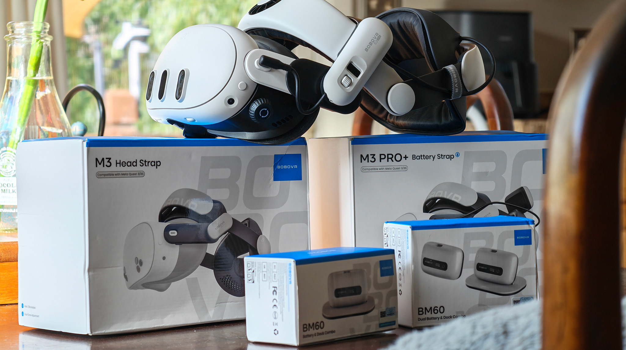 A Meta Quest 3 with a BoboVR S3 Pro attached, next to boxes of the BoboVR M3, M3 Pro, and two BM60 battery boxes