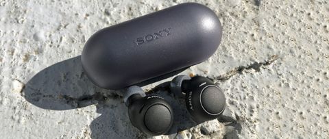 the sony wf-c500 true wireless earbuds next to their charging case on a stone surface