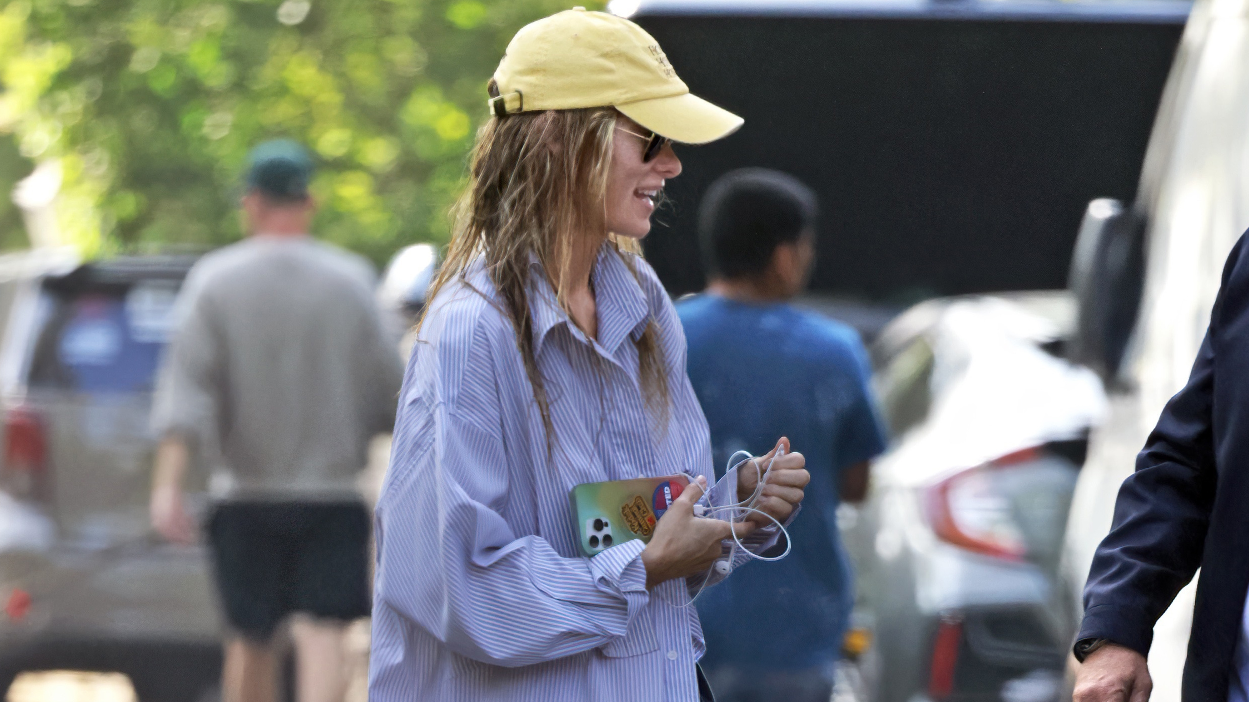 Olivia wilde wears a yellow baseball cap and blue stripe shirt.