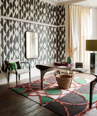 Living room with geometric patterned wallpaper, desk, chair and geometric patterned rug