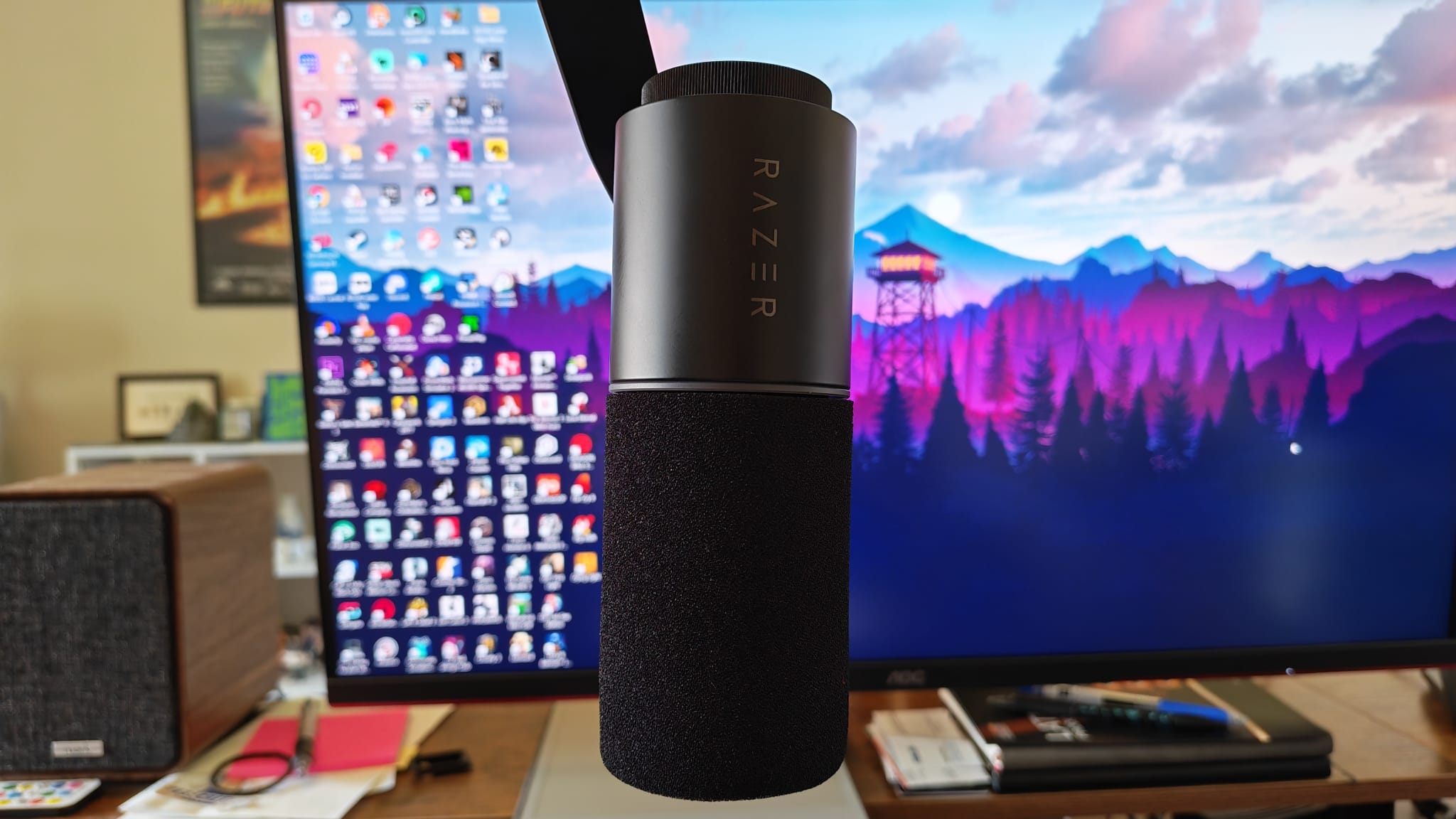 A Razer Seiren V3 Pro hanging down vertically from a boom arm in front of a gaming monitor