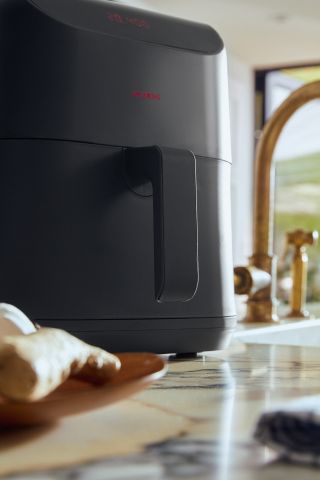 ‘Crsp 6QT’ air fryer. A black air fryer on a white marble kitchen counter.