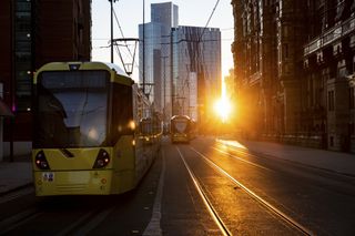 Cable cars moving along street at sunset in Manchester, England.