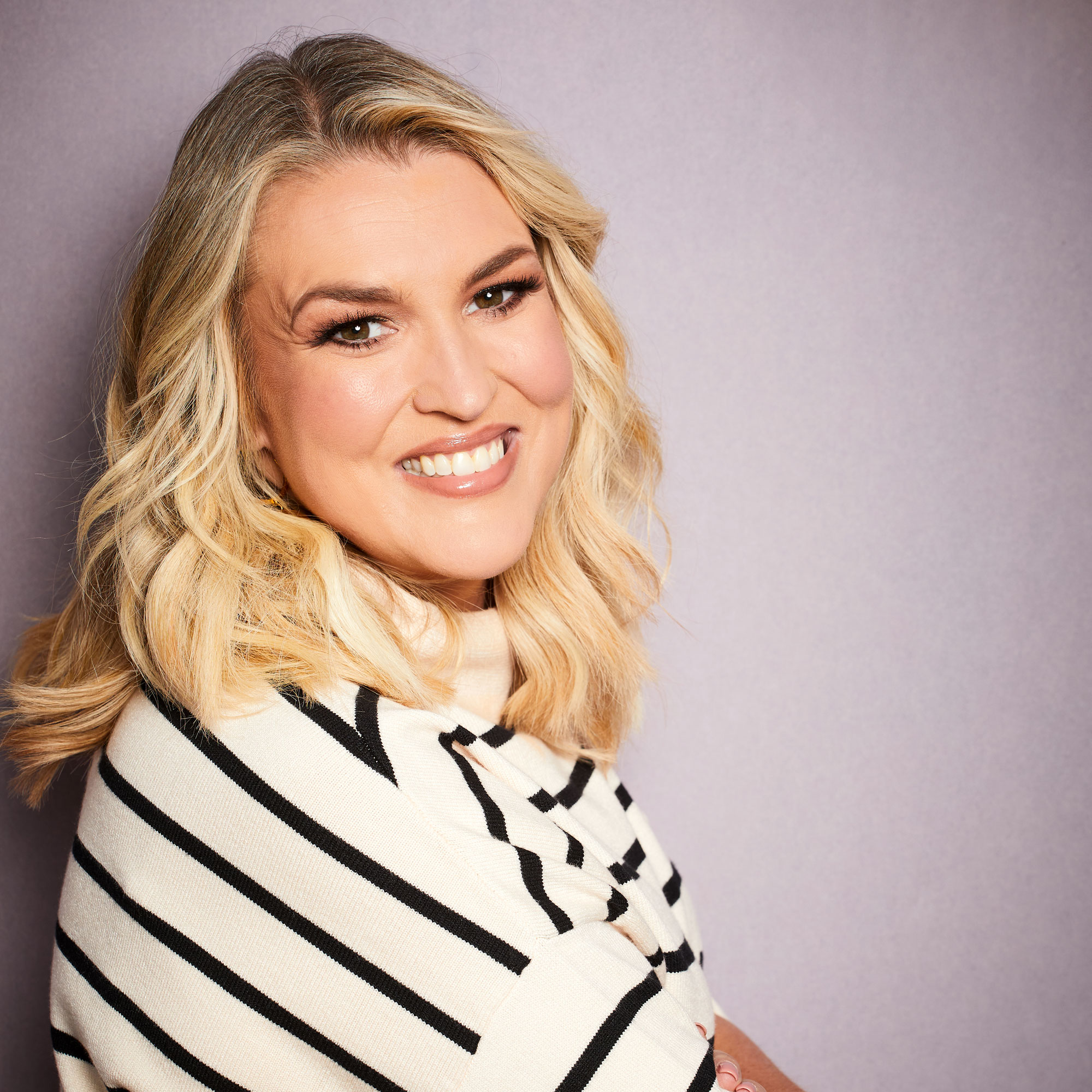 Sara Davies with blonde curled hair and white top