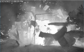 still from a black-and-white video showing a prototype space module exploding and pieces flying