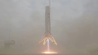 close-up view of a white rocket hovering just above the ground, with blue flame blasting from its base