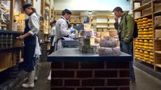 Neals Yard Dairy cheese shop interior with racks of cheeses at Borough Market London Bridge Southwark London