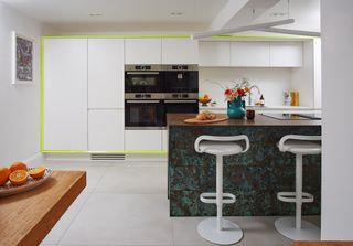 A modern kitchen with white slab cabinetry, a blue island, and large white monolithic floor slabs