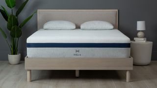 Best mattress in a box: Helix Midnight mattress on a wooden bedframe, against a dark wall