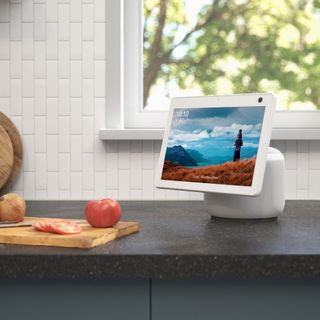Amazon Echo Show 10 (3rd Gen) on a kitchen counter next to a chopping board with fruit