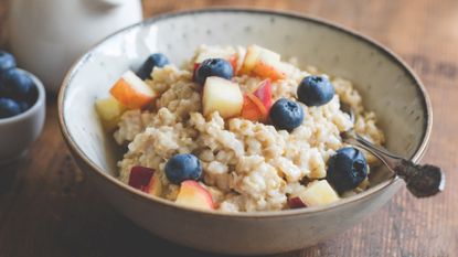 A bowl of oatmeal with blueberries and apples