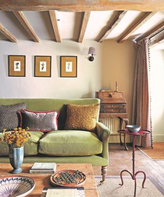 living room with green sofa, wooden beams and wooden bureau