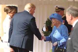 Queen Elizabeth wearing a blue coat and hat smiling and shaking hands with Donald Trump and Melania Trump on a sunny day in 2018