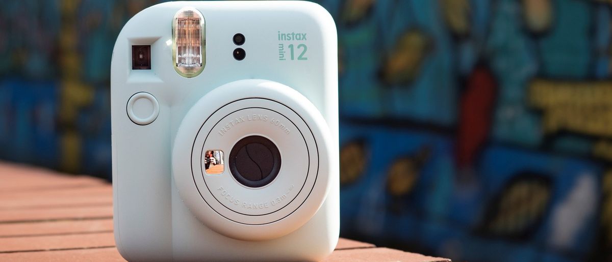 Instax Mini 12 on a brick wall in front of graffiti