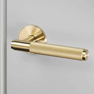 Gold door handle on a grey door to show how to make a home look expensive