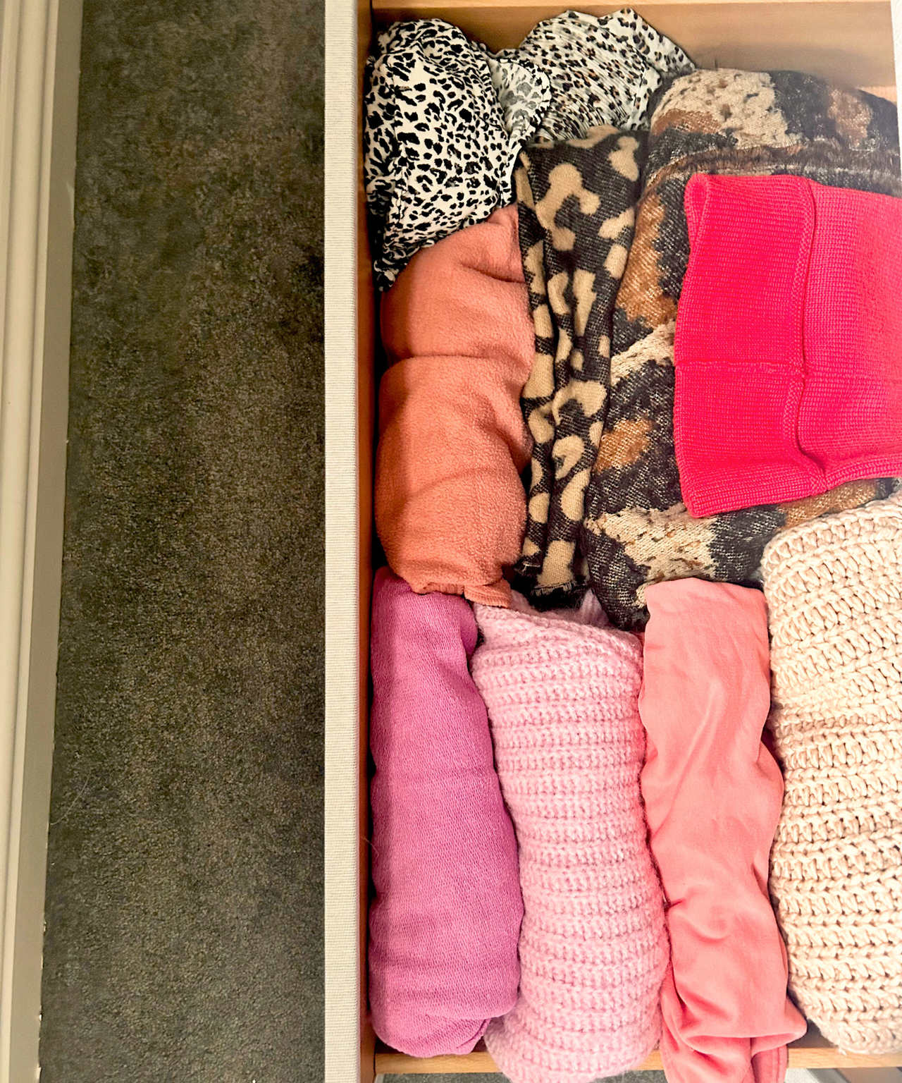 A drawer with colorful pink and leopard print clothing inside