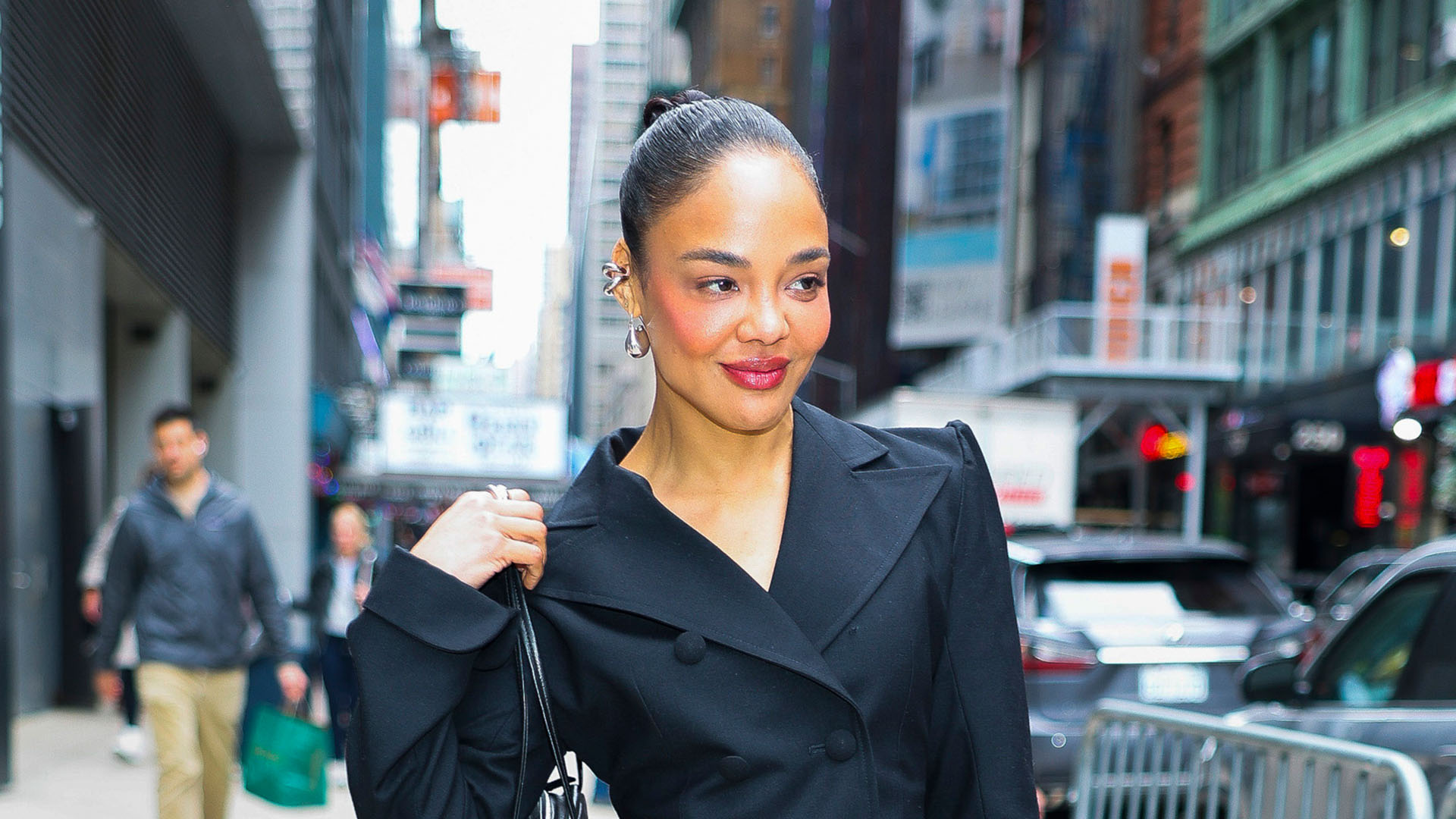Tessa Thompson wearing a black cinch waist blazer, big black pants, and black pointed-toe punps with a silver applique