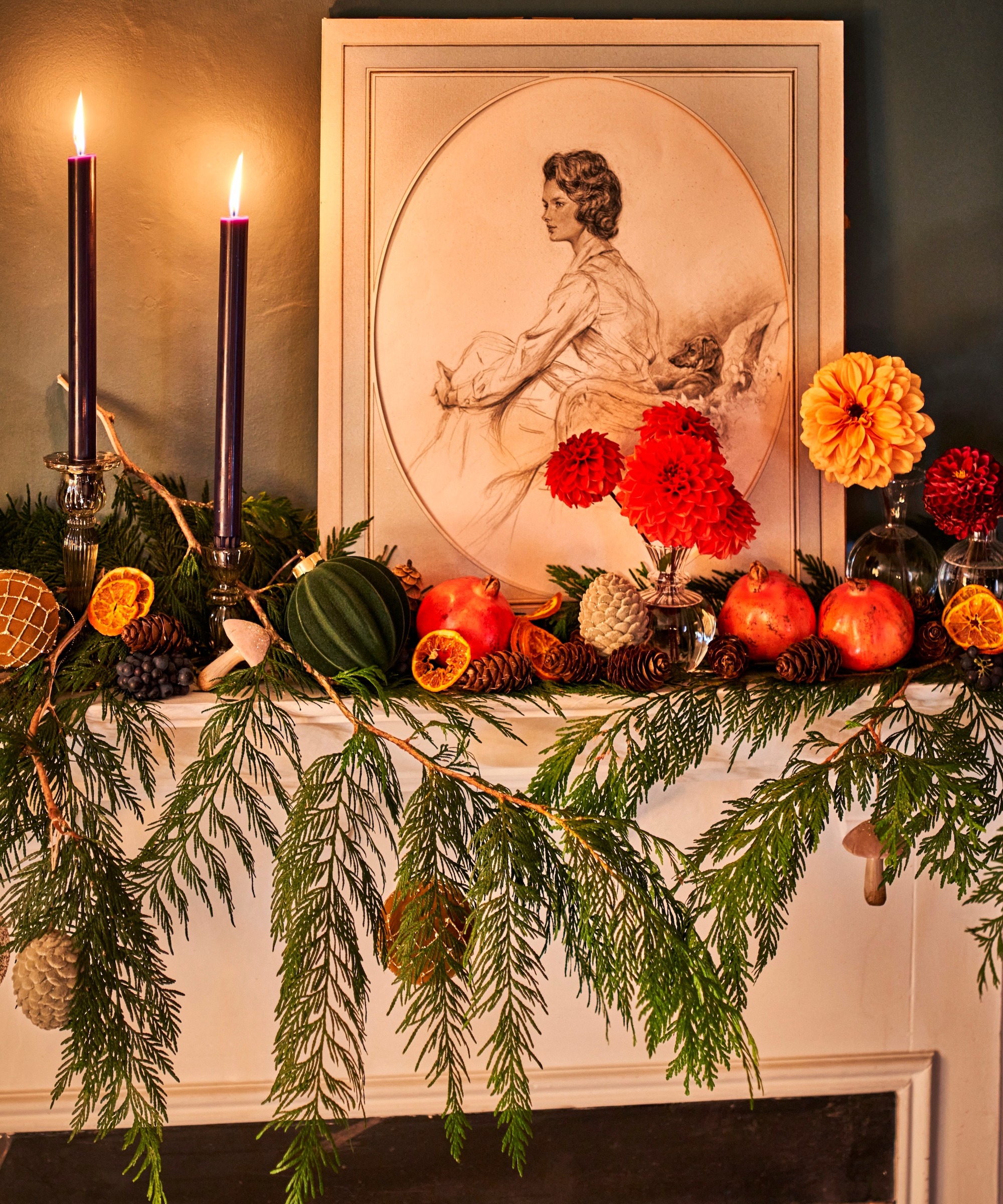 Christmas mantlepiece decorated with foliage, flowers, pomegranates, oranges and candles