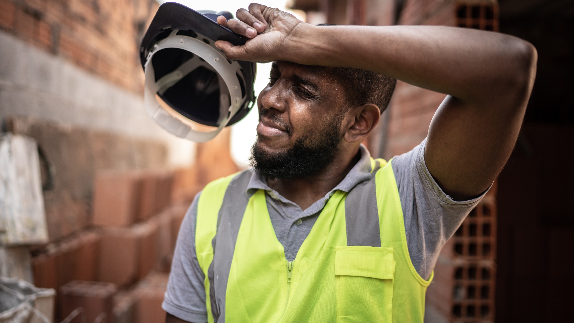 Overheated construction worker wiping sweat off his brow 